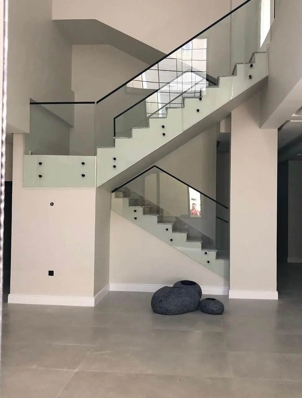 درابزين زجاجي للدرج مثبت بمسامير جانبية دائرية (Point Fixing) مع هاندريل أسود وتصميم داخلي مودرن في جدة .